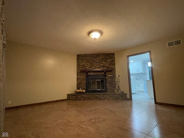 unfurnished living room with a stone fireplace, a textured ceiling, and tile patterned flooring