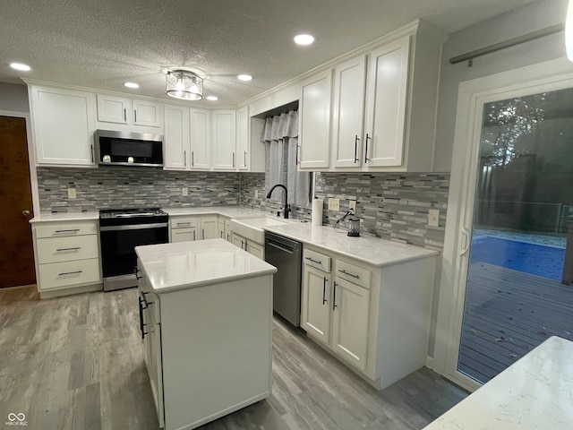 kitchen featuring white cabinetry, a textured ceiling, appliances with stainless steel finishes, and a center island