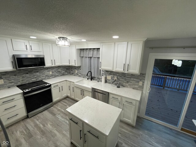 kitchen featuring appliances with stainless steel finishes, light hardwood / wood-style flooring, white cabinets, and sink