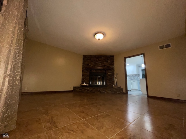 unfurnished living room with tile patterned floors, a stone fireplace, and a textured ceiling