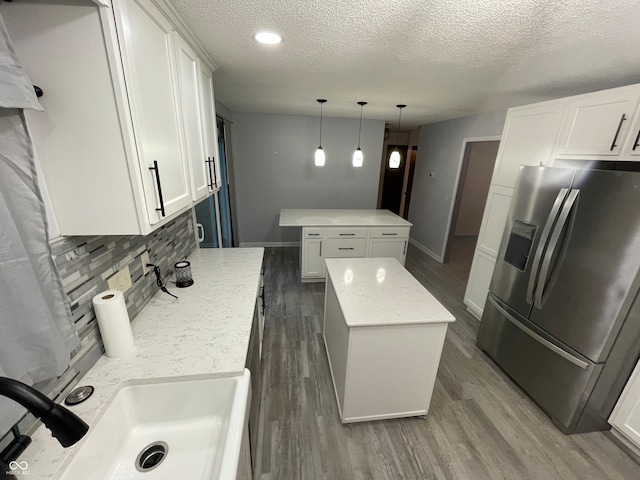 kitchen with a center island, white cabinetry, stainless steel refrigerator with ice dispenser, and decorative light fixtures