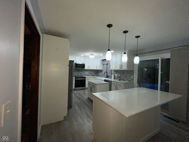 kitchen featuring appliances with stainless steel finishes, a kitchen island, white cabinetry, and tasteful backsplash