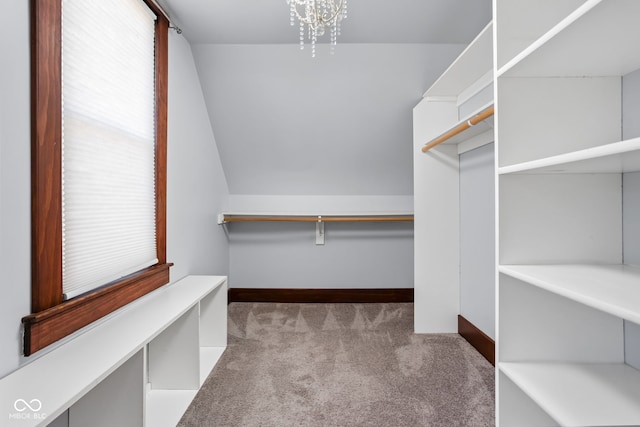 spacious closet featuring lofted ceiling, light colored carpet, and a notable chandelier