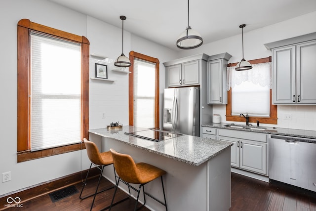 kitchen featuring sink, stainless steel appliances, a wealth of natural light, and decorative light fixtures