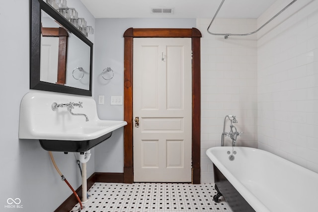 bathroom featuring tile walls, a bath, and tile patterned flooring