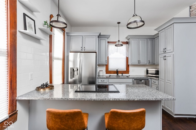 kitchen featuring dark hardwood / wood-style flooring, light stone countertops, sink, pendant lighting, and stainless steel appliances