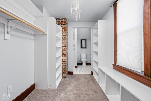 spacious closet with a notable chandelier and light colored carpet