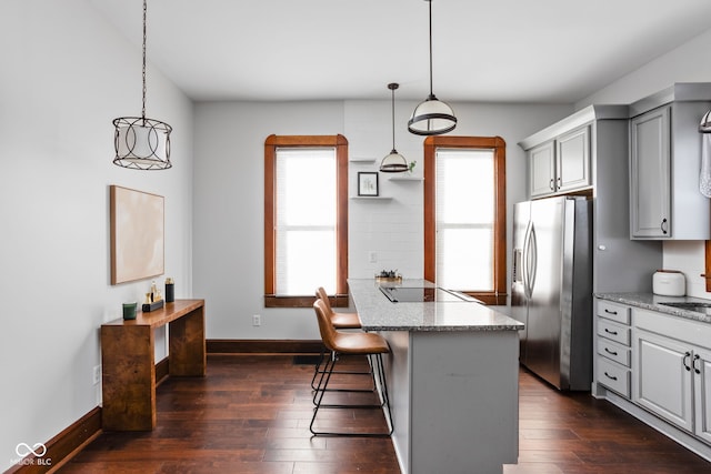 kitchen featuring a kitchen breakfast bar, dark hardwood / wood-style flooring, pendant lighting, and stainless steel fridge with ice dispenser