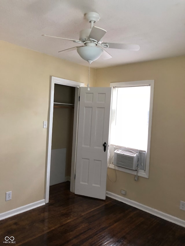 unfurnished bedroom featuring dark wood-type flooring, a closet, cooling unit, and ceiling fan