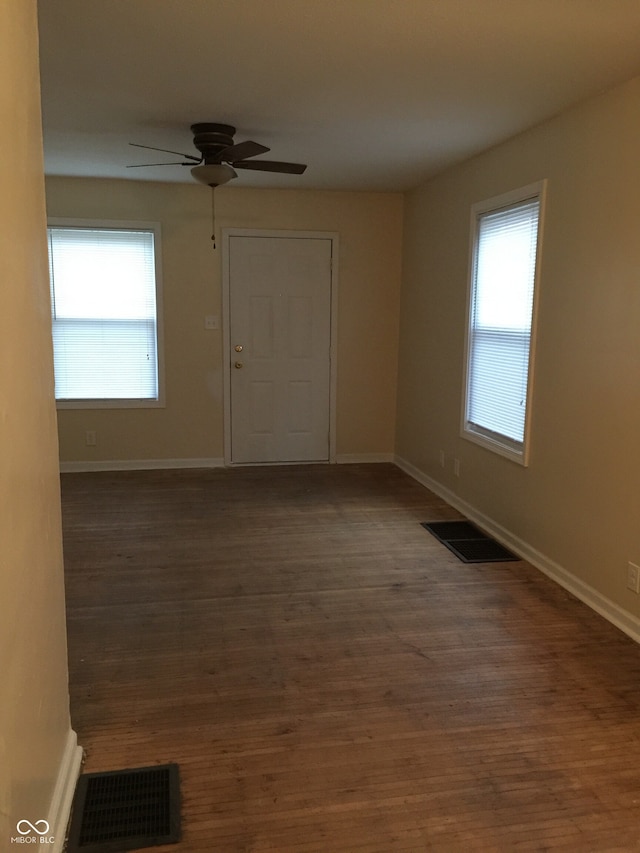 spare room featuring ceiling fan, a healthy amount of sunlight, and dark hardwood / wood-style floors