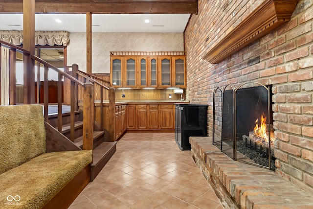 bar with beamed ceiling, light tile patterned floors, and a brick fireplace