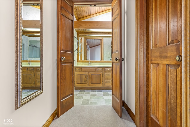 hallway featuring sink, light colored carpet, vaulted ceiling, and wood ceiling