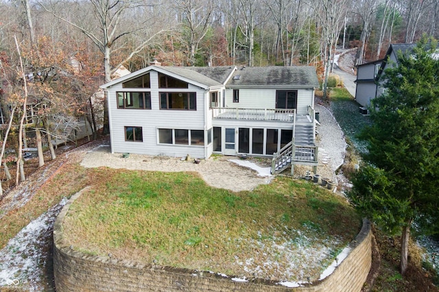 rear view of property with a deck, a lawn, and a sunroom