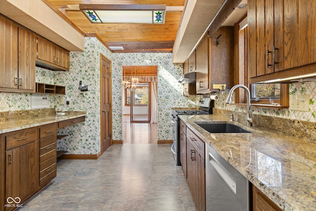 kitchen with light stone countertops, sink, an inviting chandelier, and appliances with stainless steel finishes