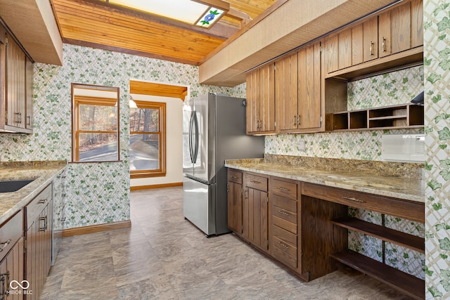 kitchen featuring stainless steel fridge, light stone countertops, wood ceiling, and sink