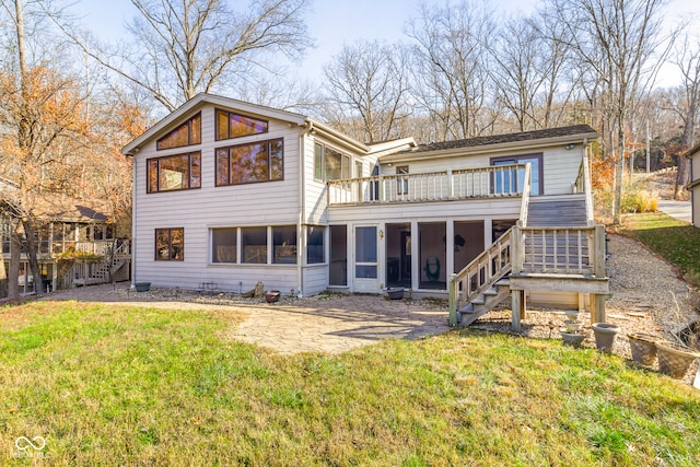 rear view of property with a patio area, a lawn, a wooden deck, and a sunroom