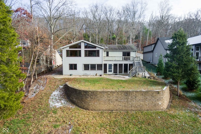 rear view of property featuring a lawn, a sunroom, and a deck