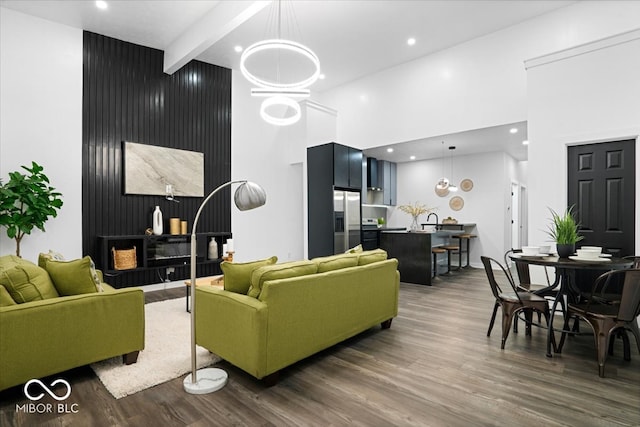 living room featuring a towering ceiling, beamed ceiling, and dark hardwood / wood-style flooring