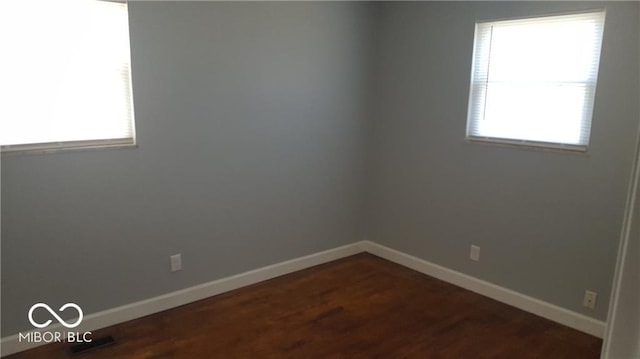 spare room with dark hardwood / wood-style floors and plenty of natural light