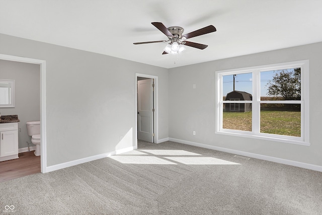 unfurnished bedroom with light carpet, connected bathroom, and ceiling fan