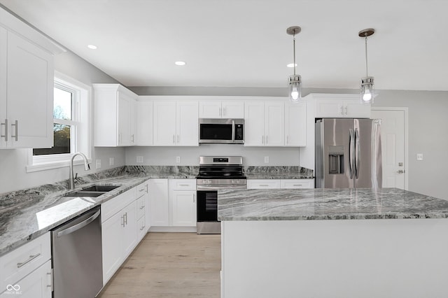 kitchen featuring a kitchen island, stainless steel appliances, sink, light wood-type flooring, and white cabinets