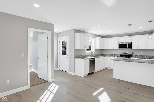 kitchen featuring light hardwood / wood-style flooring, white cabinetry, hanging light fixtures, and stainless steel appliances