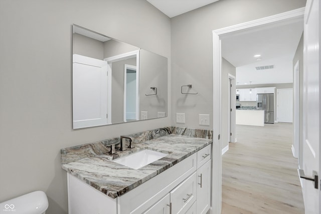 bathroom with toilet, hardwood / wood-style flooring, and vanity