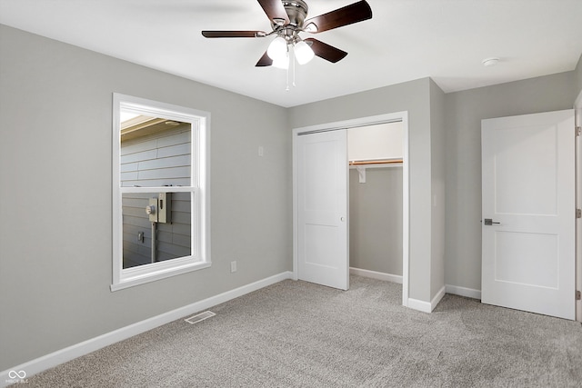 unfurnished bedroom featuring light colored carpet, a closet, and ceiling fan