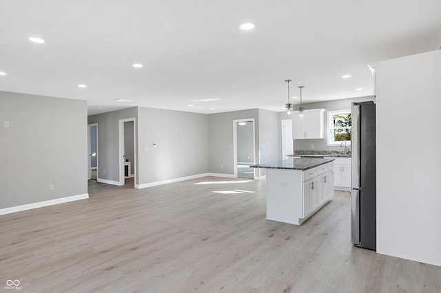 kitchen with white cabinetry, decorative light fixtures, a center island, and stainless steel refrigerator