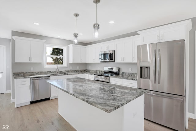 kitchen featuring a center island, appliances with stainless steel finishes, decorative light fixtures, and white cabinetry