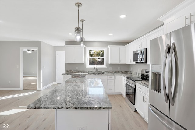 kitchen featuring sink, a center island, decorative light fixtures, white cabinetry, and appliances with stainless steel finishes