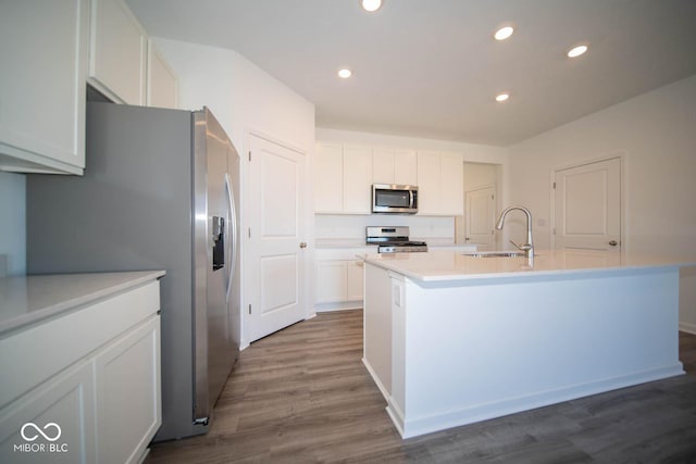 kitchen with appliances with stainless steel finishes, white cabinetry, a kitchen island with sink, and sink