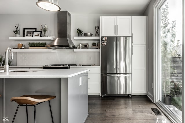 kitchen featuring wall chimney exhaust hood, stainless steel refrigerator, dark hardwood / wood-style flooring, and white cabinets