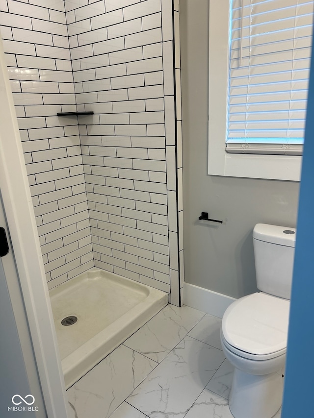 bathroom featuring toilet and a tile shower