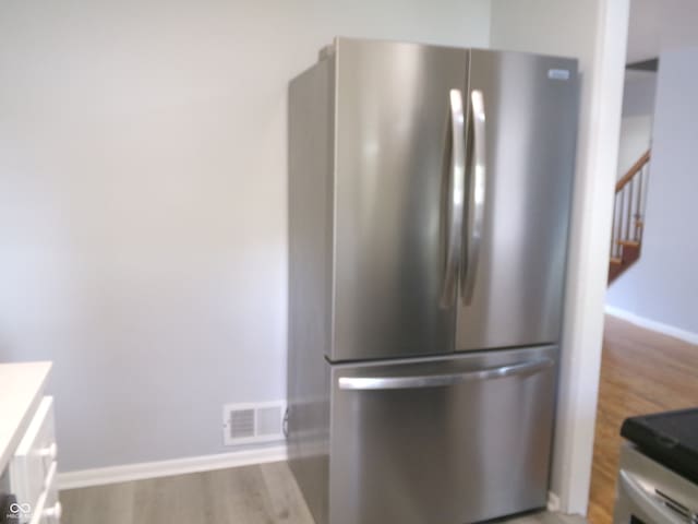 kitchen with stainless steel refrigerator and light hardwood / wood-style flooring