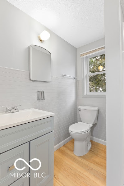 bathroom featuring vanity, hardwood / wood-style floors, a textured ceiling, and toilet