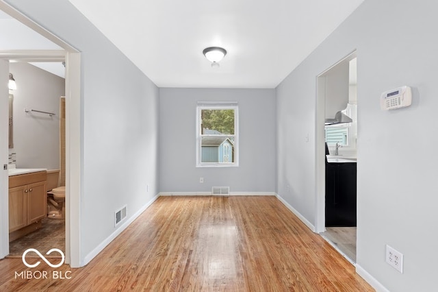 unfurnished bedroom with ensuite bathroom, sink, and light hardwood / wood-style floors