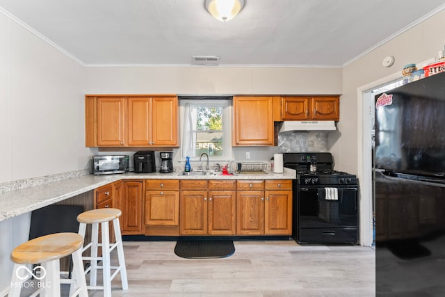 kitchen featuring decorative backsplash, light wood-type flooring, black appliances, crown molding, and sink