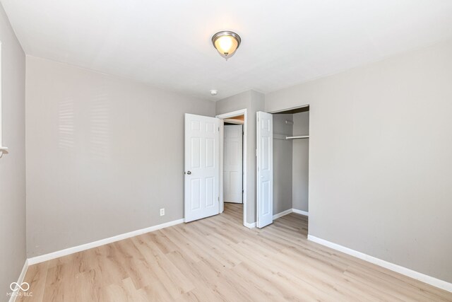 unfurnished bedroom with light wood-type flooring and a closet