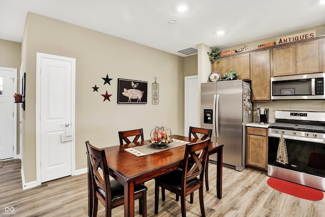 kitchen featuring tasteful backsplash, stainless steel appliances, and light wood-type flooring