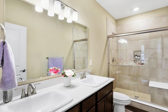 bathroom with toilet, a shower with shower door, and vanity