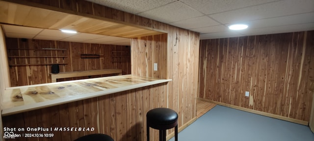 bar with wood walls and a paneled ceiling