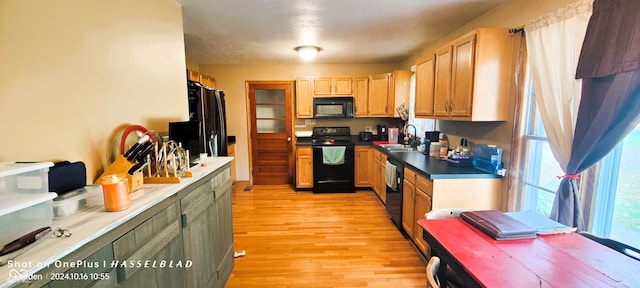 kitchen with light wood-type flooring, sink, and black appliances