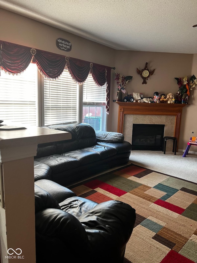 living room featuring carpet flooring, a textured ceiling, and a tiled fireplace