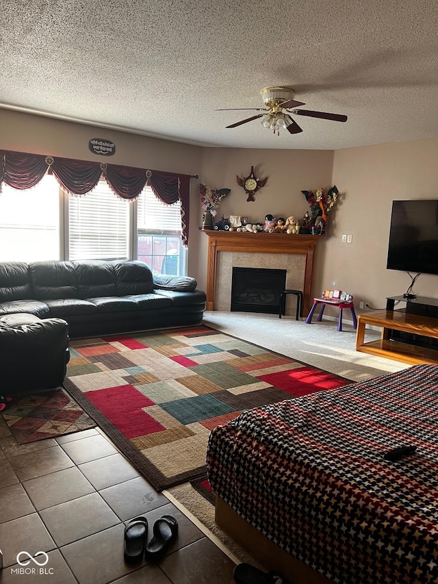 living room with a fireplace, ceiling fan, tile patterned flooring, and a textured ceiling