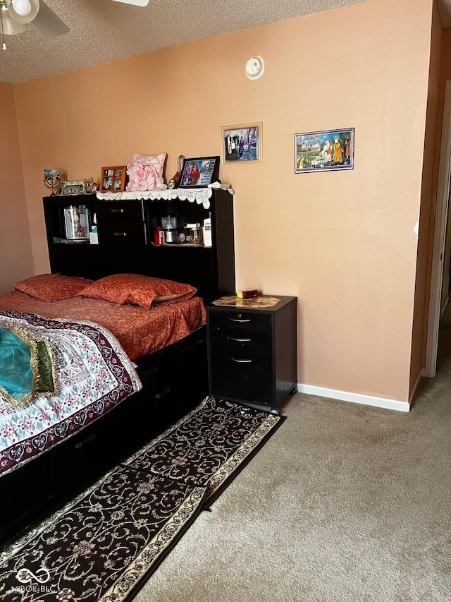 bedroom featuring ceiling fan, carpet floors, and a textured ceiling