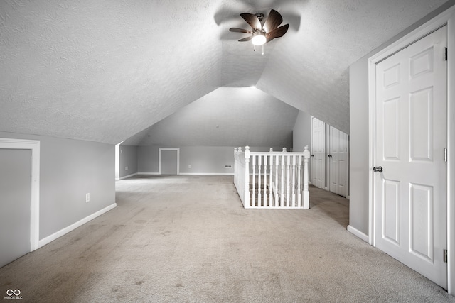 bonus room featuring lofted ceiling, ceiling fan, light carpet, and a textured ceiling