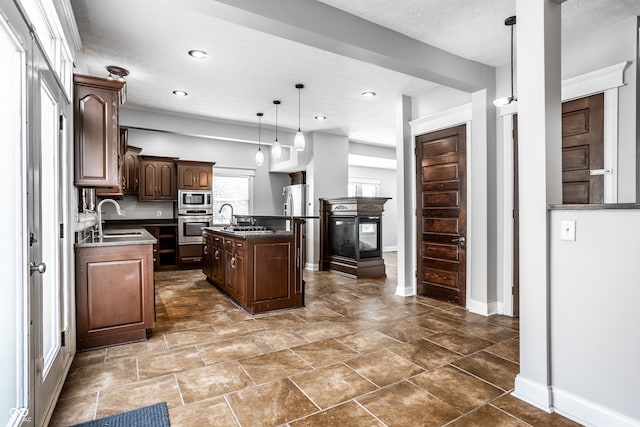 kitchen featuring a kitchen island with sink, dark brown cabinetry, sink, hanging light fixtures, and appliances with stainless steel finishes