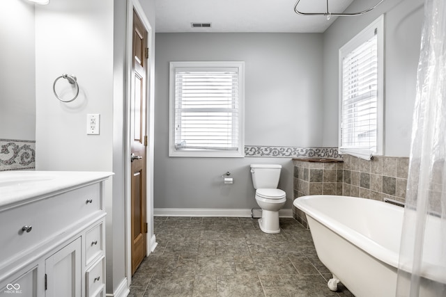 bathroom featuring plenty of natural light, a bathtub, vanity, and toilet