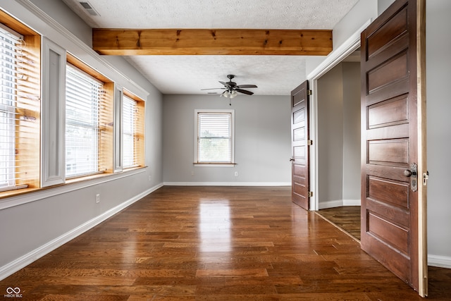 empty room with beam ceiling, ceiling fan, dark wood-type flooring, and a textured ceiling